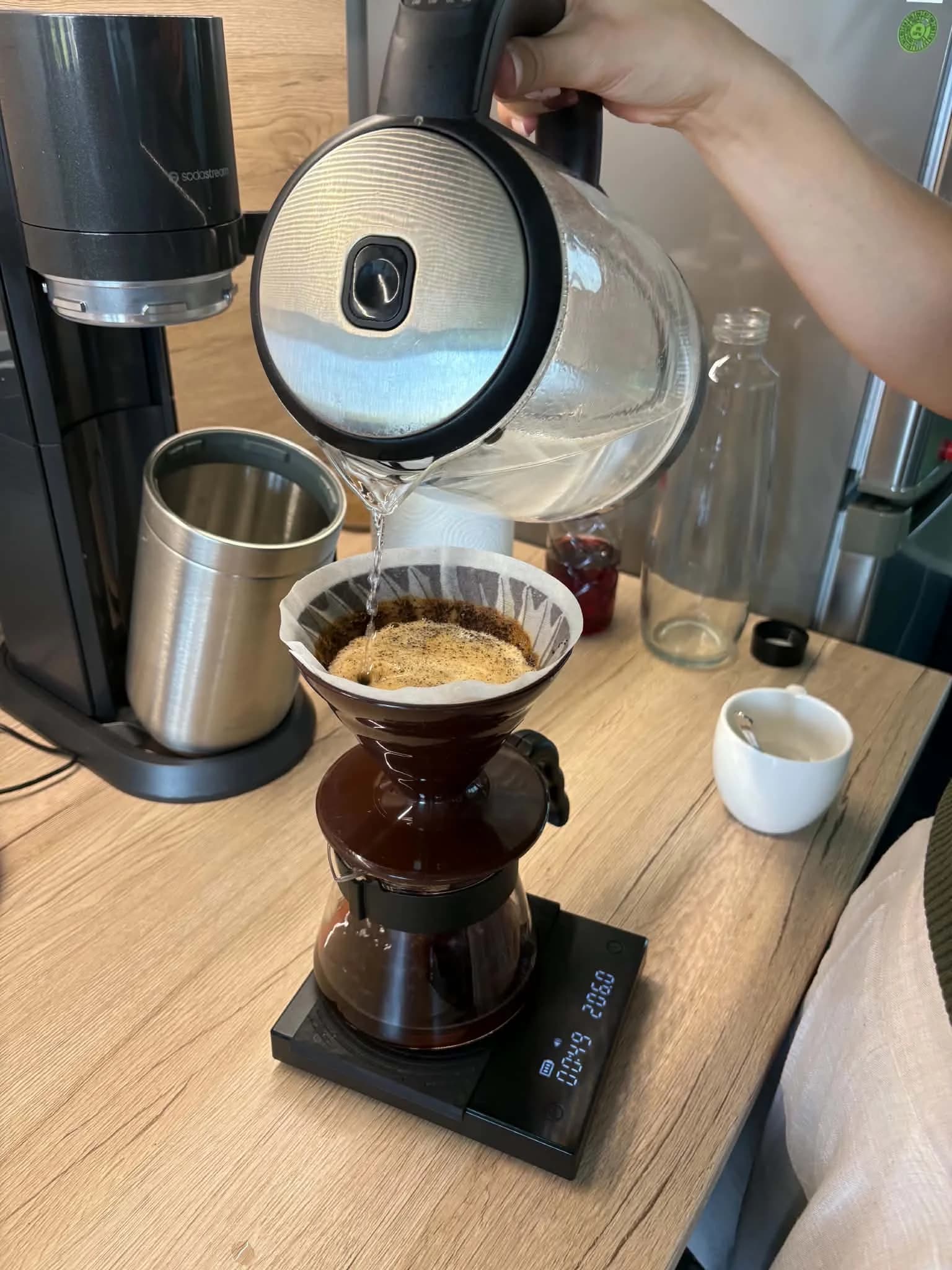 Kávový filtr V60 s bílým papírovým filtrem uprostřed, vlevo french press, vpravo espresso a moka konvička